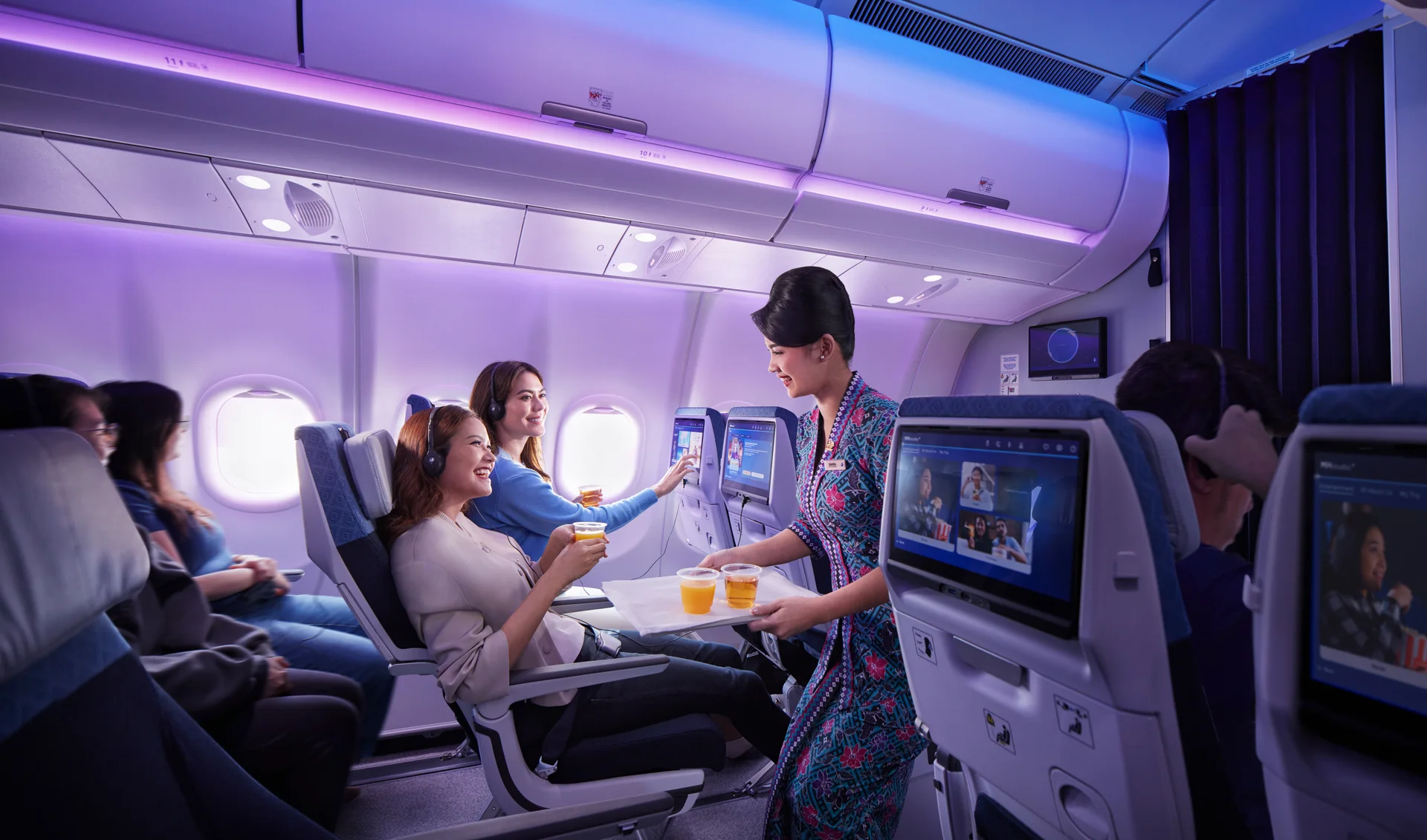 Malaysia Airlines cabin crew welcoming passengers with drinks on board